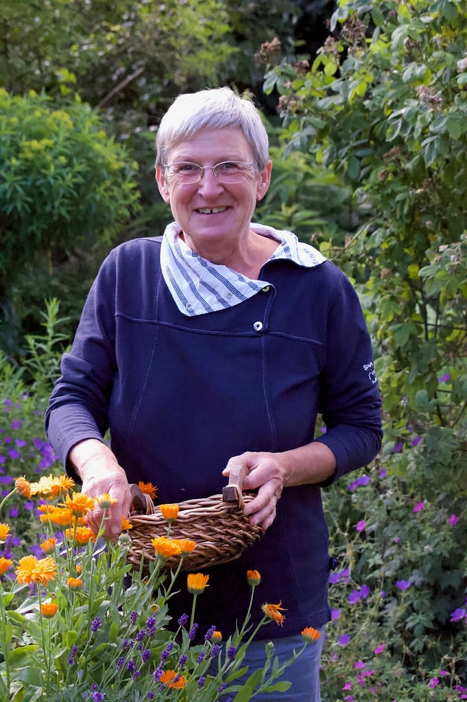 Brigitte Dammann im Garten mit Kräutern